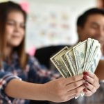 A young woman holding out cash