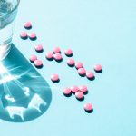 A collection of pills that could be placebos next to a glass of water