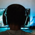 A gamer wearing headphones and playing on the computer