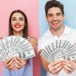 Excited young couple looking excited while holding money