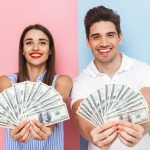 Excited young couple holding money