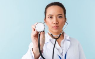 Woman doctor posing in front of blue wall