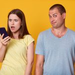 Woman looking at her boyfriend's phone in shock