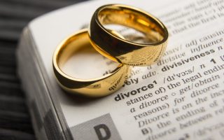 A pair of rings sitting on the dictionary definition of "divorce"