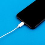 A smartphone being charged on a blue background