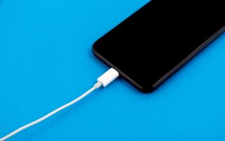 A smartphone being charged on a blue background