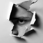 A man looking through a paper wall, symbolizing narcassism