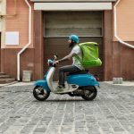 A man driving a scooter doing gig work