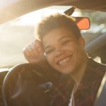 A young and happy teen behind the wheels of a car