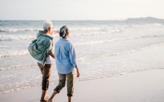 An older couple walking together on the beach