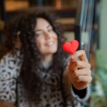 A woman who is in love handing over a red paper heart