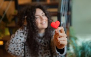 A woman who is in love handing over a red paper heart