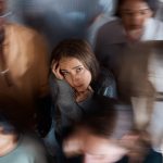 An anxious woman in a group of people looking unhappy