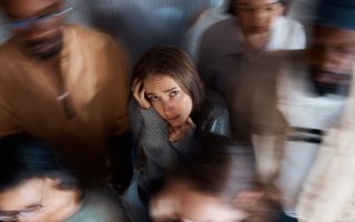 An anxious woman in a group of people looking unhappy