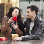 A young couple on a date holding a red heart