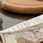 Tips and receipt on wooden table after two friends decided on splitting the bill at a restaurant