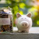 A piggy bank next to a jar full of coins