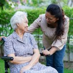 Elderly woman in a wheelchair looked after by adult daughter
