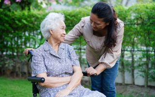 Elderly woman in a wheelchair looked after by adult daughter