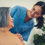 A caregiver resting her hands on the shoulders of a senior patient.