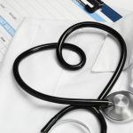 Medical uniform, stethoscope in shape of heart and documents