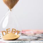 The word debt inside an hourglass full of sand