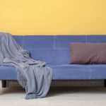 Cheap furniture: an old blue sofa in a yellow room