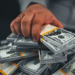 A hand takes money on a black background