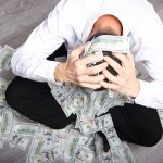 An unhappy man covered in cash