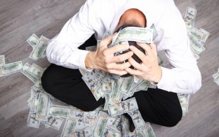 An unhappy man covered in cash