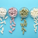 Different vitamin pills on light blue background