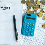A calculator, coins, and notebook for a budget