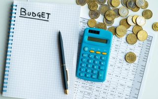 A calculator, coins, and notebook for a budget