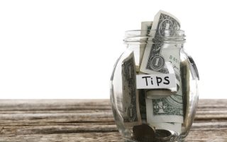 Glass jar with tips on wooden table against white background