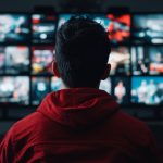A man sitting in front of multiple televisions