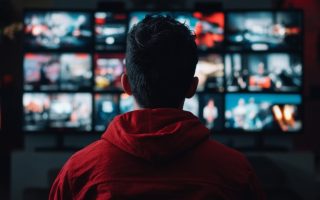 A man sitting in front of multiple televisions