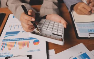 A man pointing out figured to someone else on a calculator