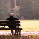 Old man sitting on a bench in autumn