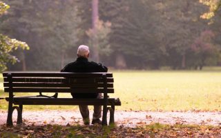 Old man sitting on a bench in autumn