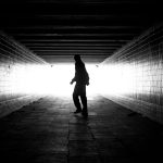 A victim of talking walking down a dark tunnel in black and white