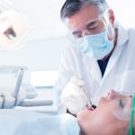 Dentist examining a patients teeth in the dentists chair at the dental clinic