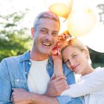 Happy couple holding balloons at the park on a sunny day