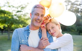 Happy couple holding balloons at the park on a sunny day