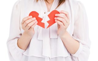 A young friend holding a ripped paper heart after a tough breakup