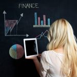 A woman holding a tablet and looking at financial data