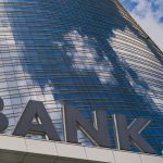 A bank sign outside of a tall building