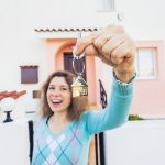 Happy young woman In Front of New Home with New House Keys close up