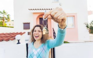 Happy young woman In Front of New Home with New House Keys close up