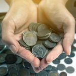 A pair of hands holding a lot of coins