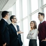 Professional business people standing around in informal group chatting
